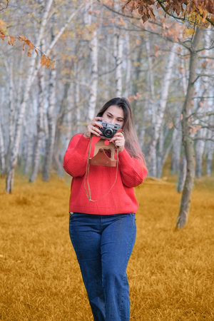 Portrait of a photographer covering her face with the vintage camera, taking a pictureの写真素材
