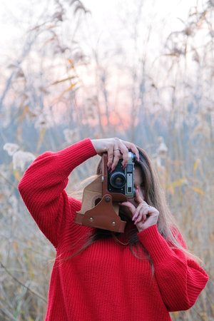 Portrait of a photographer covering her face with the vintage camera, taking a picture
