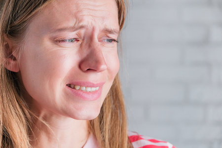 close up of sad young woman with tired eyes looking away and crying, having problems and emotional...