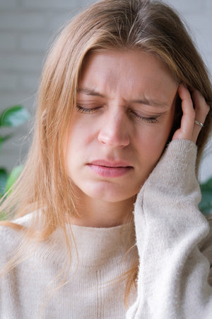 upset millennial woman standing indoors at home looking, facial expression worry about trouble or problemの写真素材