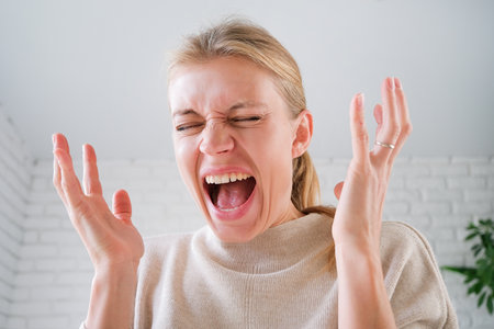 upset millennial woman standing indoors at home looking, facial expression worry about trouble or problemの写真素材