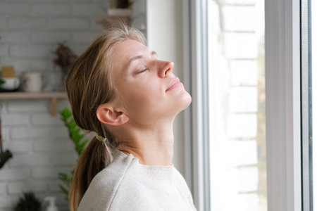 young millennial woman waking up in the morning looking to the window