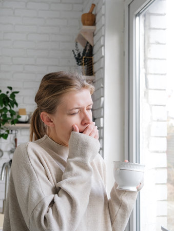 young millennial woman waking up in the morning looking to the windowの写真素材