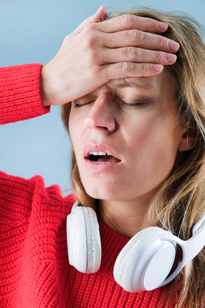 close up of young woman wearing headphones having headache touching head, having problems and emotional stress or painの写真素材