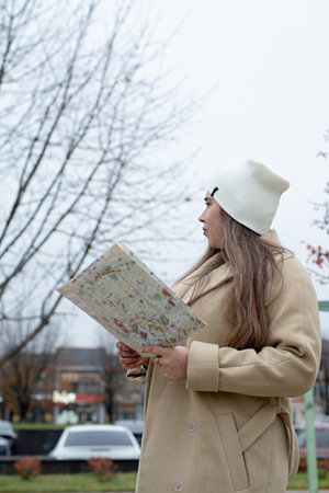 young brunette woman standing at the street looking at paper mapの写真素材