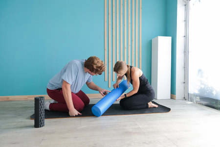 sportive man and woman training using mfr or massage roll at home. Couple doing exercises together...