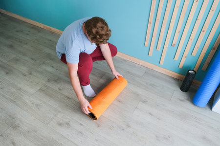 sportive man training using mfr or massage roll at home.Caucasian man unrolling the matの写真素材