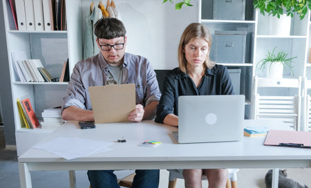 Teamwork meeting, tablet and business people in office workplace. millennial man and woman working in small office discussing documentsの写真素材