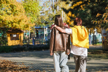 happy mother with her daughter walking in autumn park, view from behindの写真素材