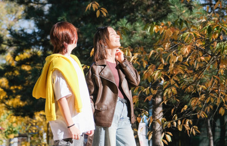 happy mother with her daughter walking in autumn park enjoying the sunの写真素材