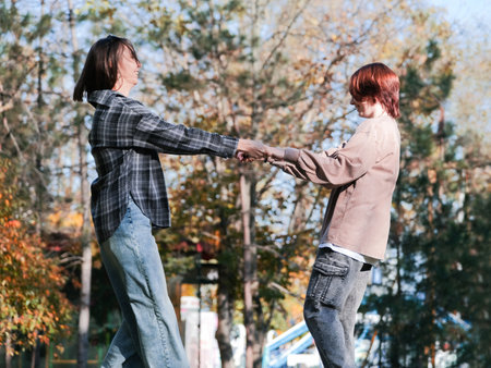 happy mother with her daughter walking and dancing in autumn parkの写真素材