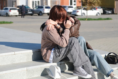 teen girl and mother sitting on the stairs huggingの写真素材