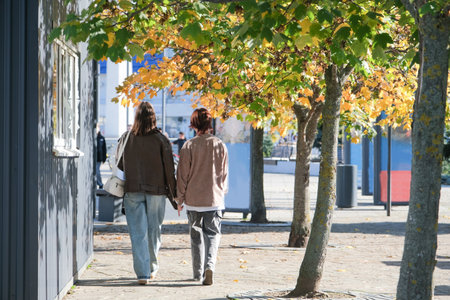happy mother with her daughter hugging walking in autumn street, view from behindの写真素材