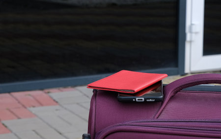Purple suitcase with passport and smartphone on airport entrance backgroundの写真素材