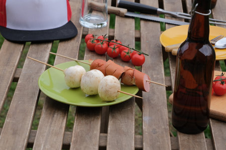 high ange view of wooden picnic table with sausages and mushrooms near tent over green grass lawnの写真素材
