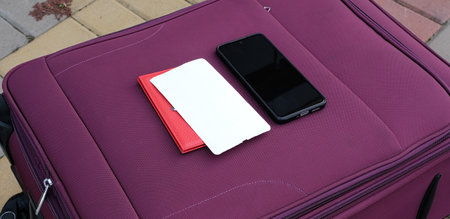 Purple suitcase with passport and smartphone on airport entrance backgroundの写真素材