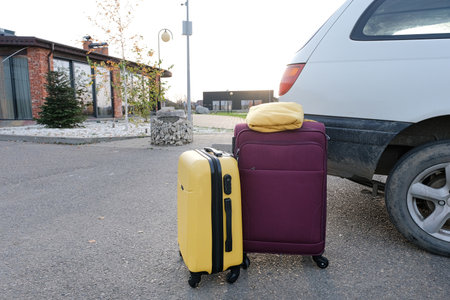 yellow and purple suitcases on parking lot near car. Concept of travel and transportationの写真素材