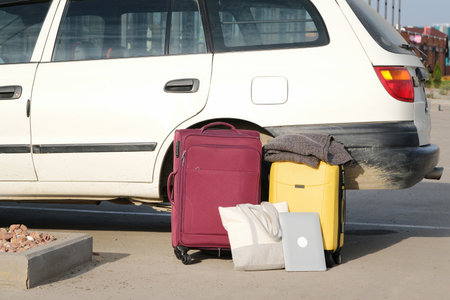 pile of suitcases and bags on parking lot near car. Concept of travel and transportationの写真素材