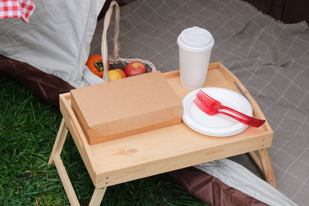 disposable eco tableware on picnic table in tent over green grassの写真素材