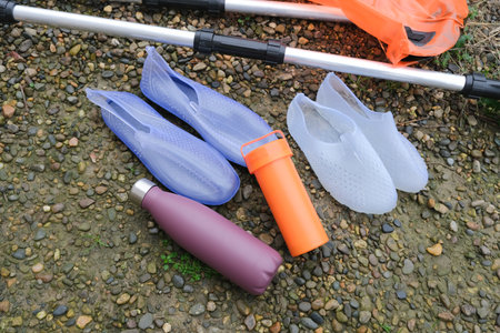 sup accessories repair kit, paddle and water shoes on stony beach high angle view