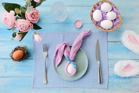 Easter table setting, egg with bunny ears on plate on the table decorated for Easter, top view