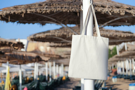 Mockup shopper handbag hanging on the beach umbrella. shopping eco reusable bag in vacation