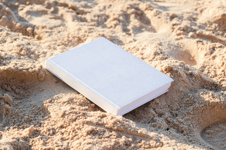 blank white book mockup on sandy beach, hard shadow
