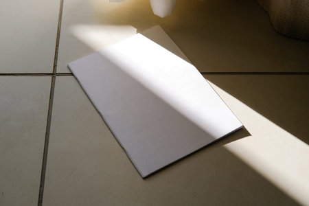 empty magazine mockup on tile floor in the room with curtain, shadow overlay. For advertising, brand...