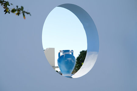 Blue antique vase in round hole in decorative wall outdoor, day sunlight. Exterior decor