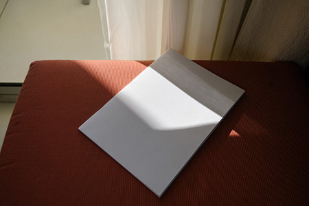 empty magazine mockup on soft chair in the room, shadow overlay, hard light. For advertising, brand...