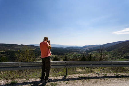 Man taking pictures of a mountain viewの写真素材