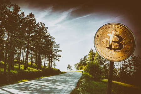 Bitcoin on a road sign with a road in the backgroundの写真素材