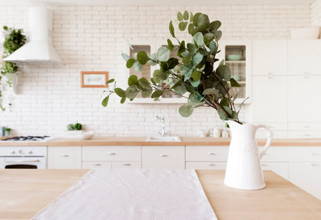 Interior of modern kitchen with white brick wall and table with vase of eucalyptus