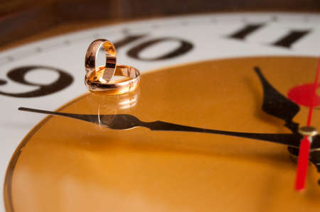photo of wedding rings on yellow clockの写真素材
