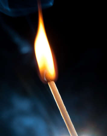 Photo of a burning match in a smoke on a black backgroundの写真素材