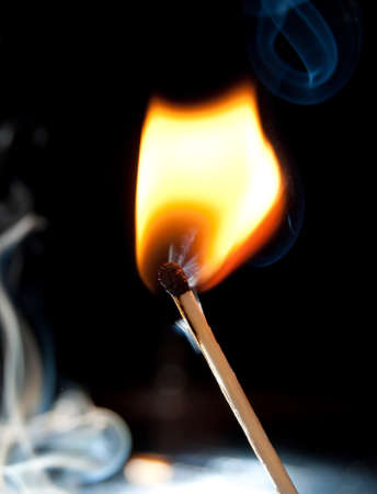 Photo of a burning match in a smoke on a black backgroundの写真素材