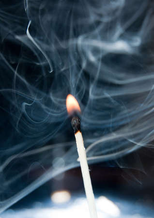 Photo of a burning match in a smoke on a black backgroundの写真素材