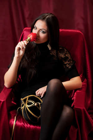 The beautiful woman with a rose on red backgroundの写真素材