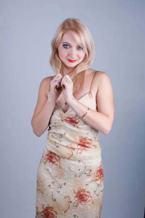 portrait of a beautiful young lady in beige dress playing with hairの写真素材