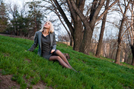 beautiful girl sitting on the grass in the parkの写真素材