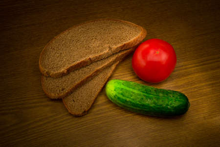 Bread, tomato and cucumber on a wooden backgroundの写真素材