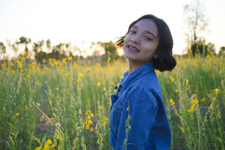 Happy Asian young girl at flower garden on summer with nice sky.
