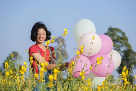 Happy Asian young girl at flower garden on summer with nice sky.の写真素材