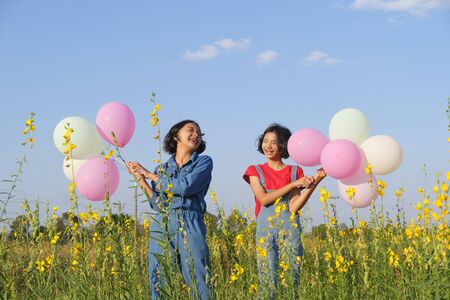 Two happy Asian young girl at flower garden on summer with nice sky.の写真素材