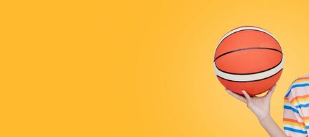 Basketball in hand with yellow background.の写真素材