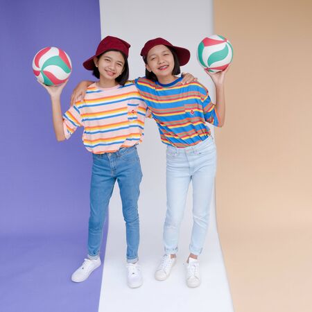 Happy young asian girls with volleyball and pastel background.
