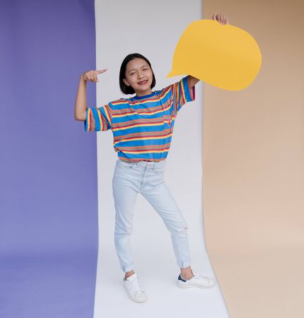 Happy asian young girl hold yellow board with pastel background.