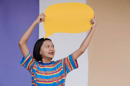 Happy asian young girl hold yellow board with pastel background.の写真素材