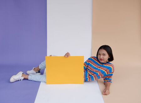 Happy asian young girl hold yellow board with pastel background.の写真素材