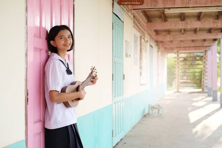 Asian young girl playing ukulele at school.の写真素材